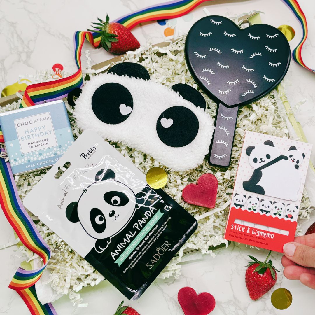 Collection of panda-themed products including face masks, a heart-shaped mirror, and stationery items on a white surface with strawberries and ribbons.