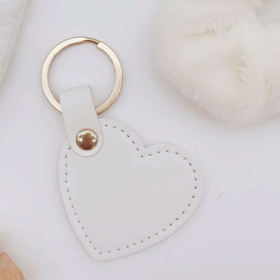 Heart-shaped keychain with gold ring on a white surface