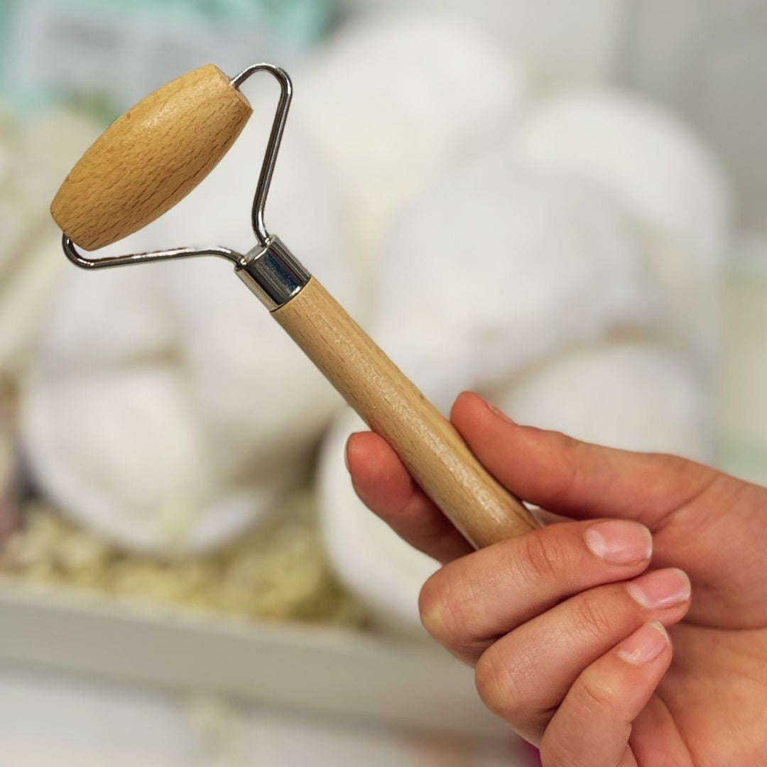 Hand holding a wooden roller with a blurred background
