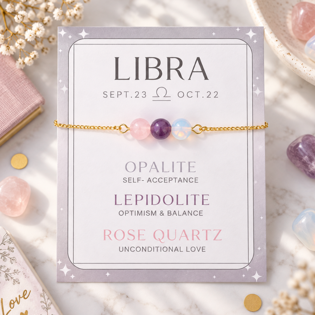 A gold chain bracelet with three beads (pink opalite, purple lepidolite, and light blue rose quartz) displayed on its lavender card, which lists astrological meanings for Libra.