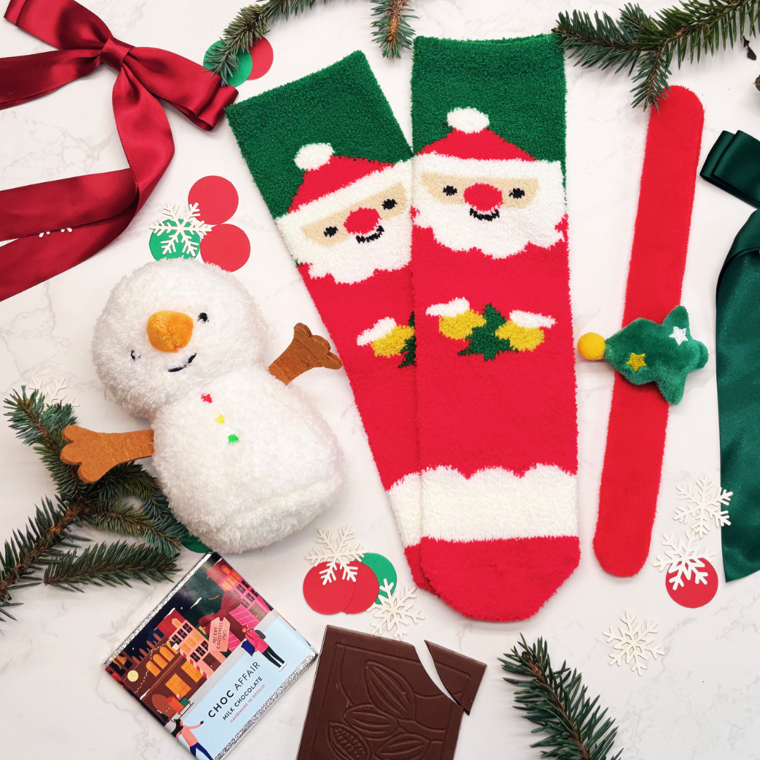 Christmas-themed items including socks with Santa and snowman designs, a snowman figurine, and chocolate on a white background.