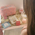 Gift box with various items including a gingham make up bag, gold earrings, and birthday themed goodies.
