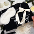 Cotton feel black pyjamas with white  fluffy eye mask, and satin white hair ribbon, held against a decorative giftbox.
