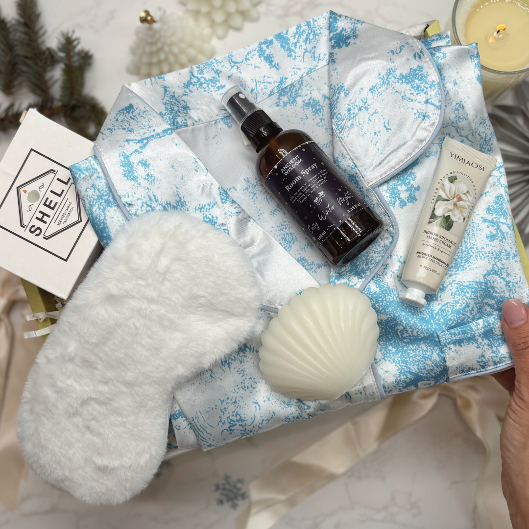 Satin feel pyjamas. Bath and body products including a room spray, hand cream, and candle on a decorative gift box.