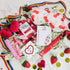 Assorted cherry-themed products including a mask, lip balm, and chocolate on a white background with strawberries and rainbow elements.