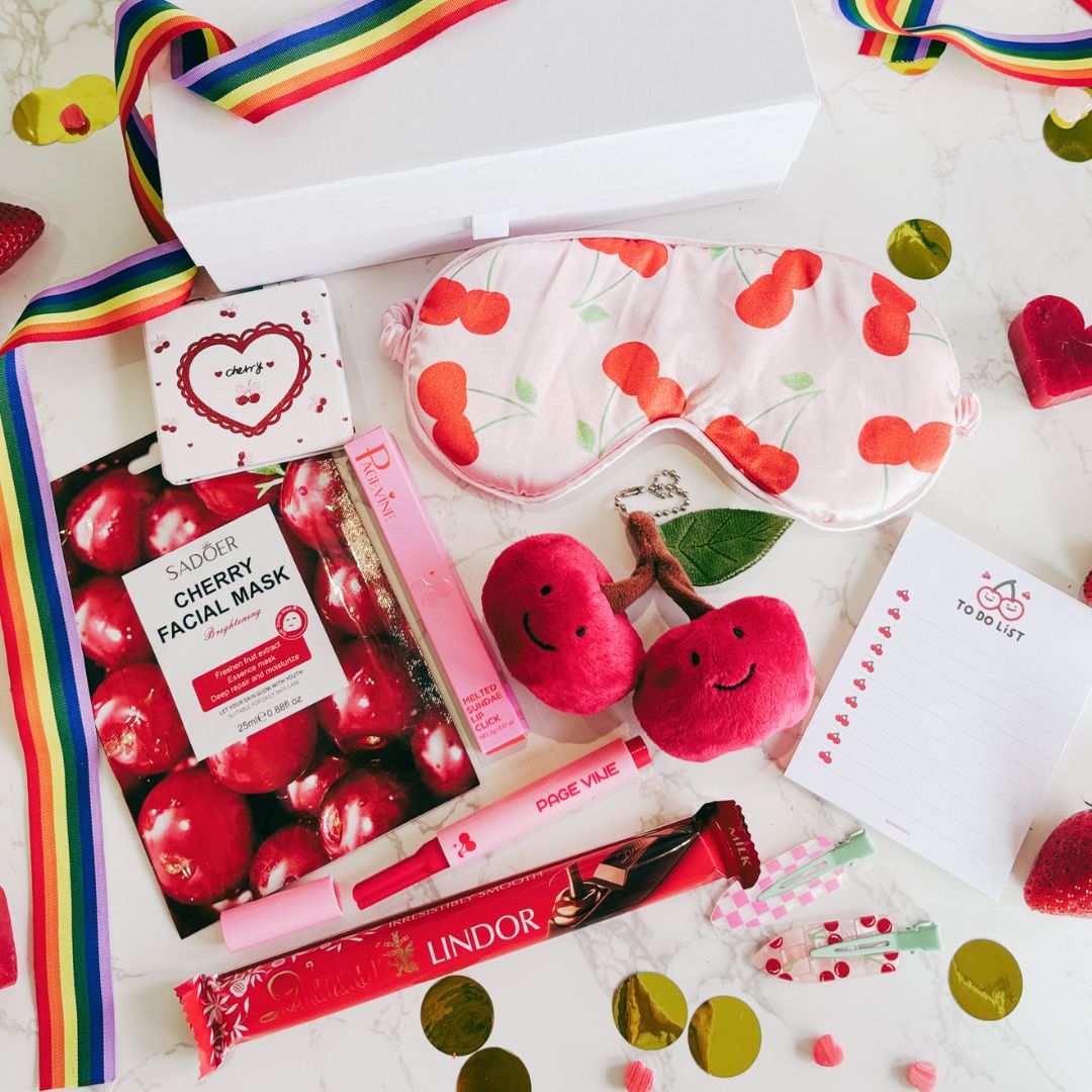 Cherry-themed products including a facial mask, lip balm, and candy on a white background with confetti.