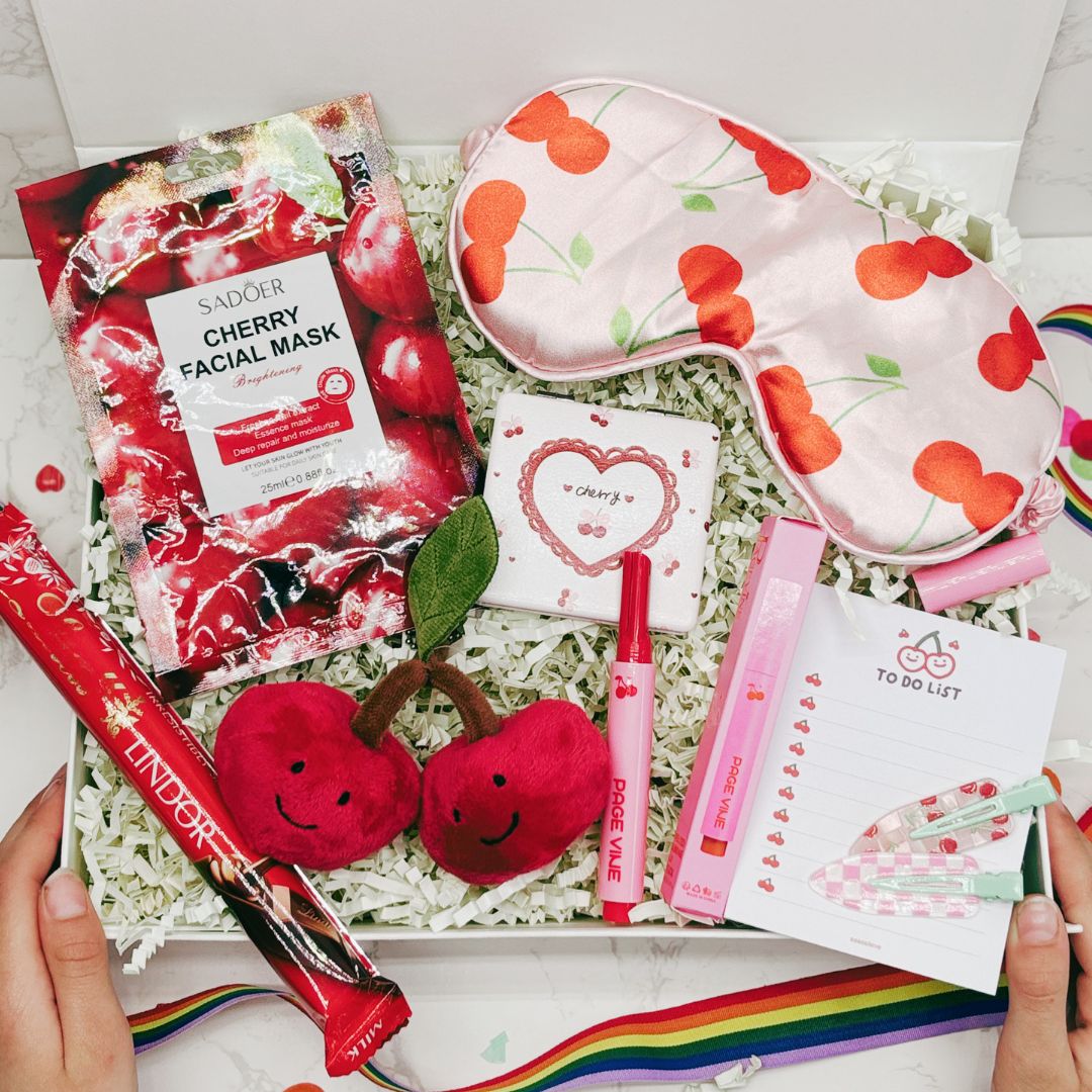 Cherry-themed products including a facial mask, sleep mask, and stationery items in a box.