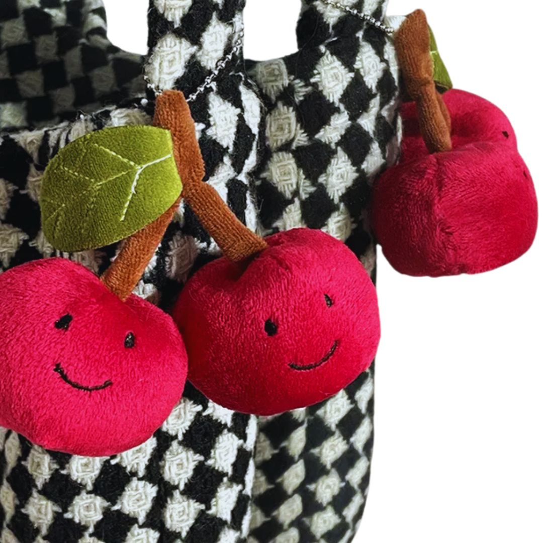 Red plush cherries with smiling faces on a checkered fabric background
