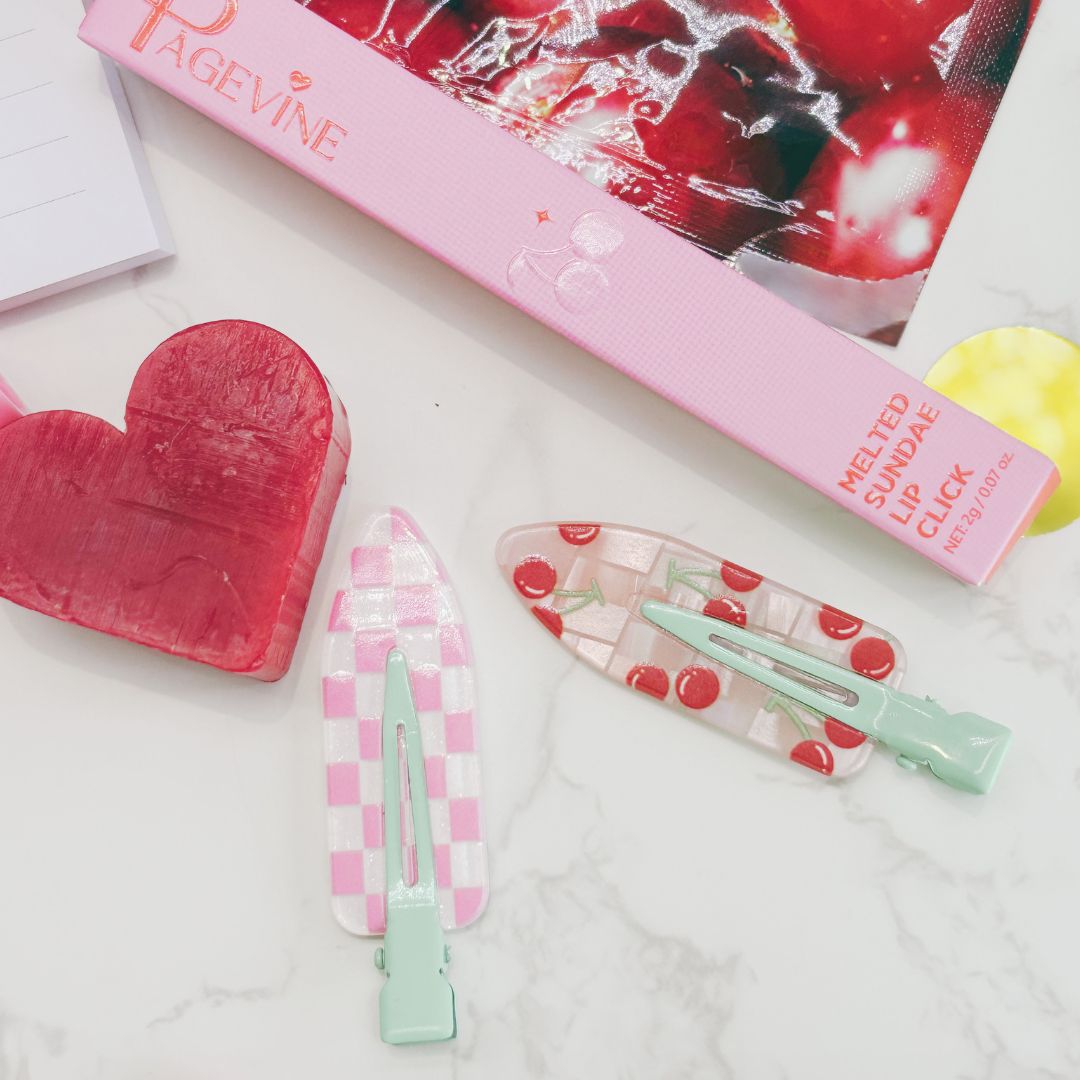 Heart-shaped soap, pink hair clip, and cherry-themed lip balm on a white surface.
