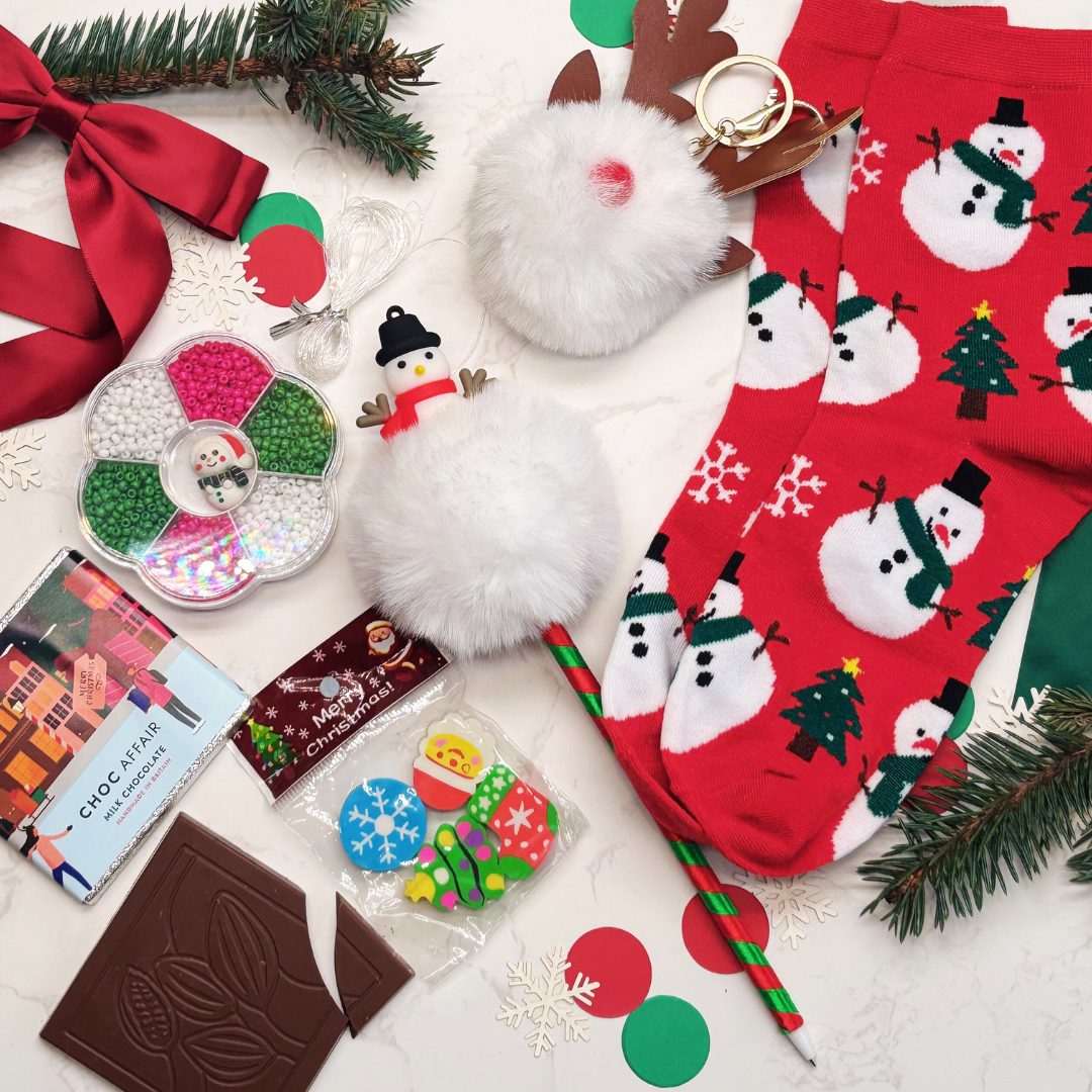 Collection of Christmas-themed items including stationary, keyring, socks, chocolate, and decorative items on a white surface.