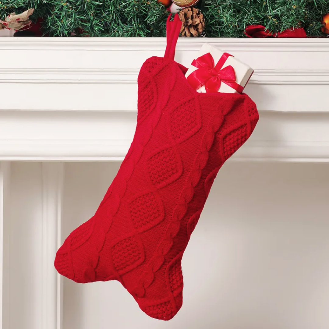 Dog Christmas Stocking. Red bone knitted Christmas stocking with a gift on a fireplace mantle.