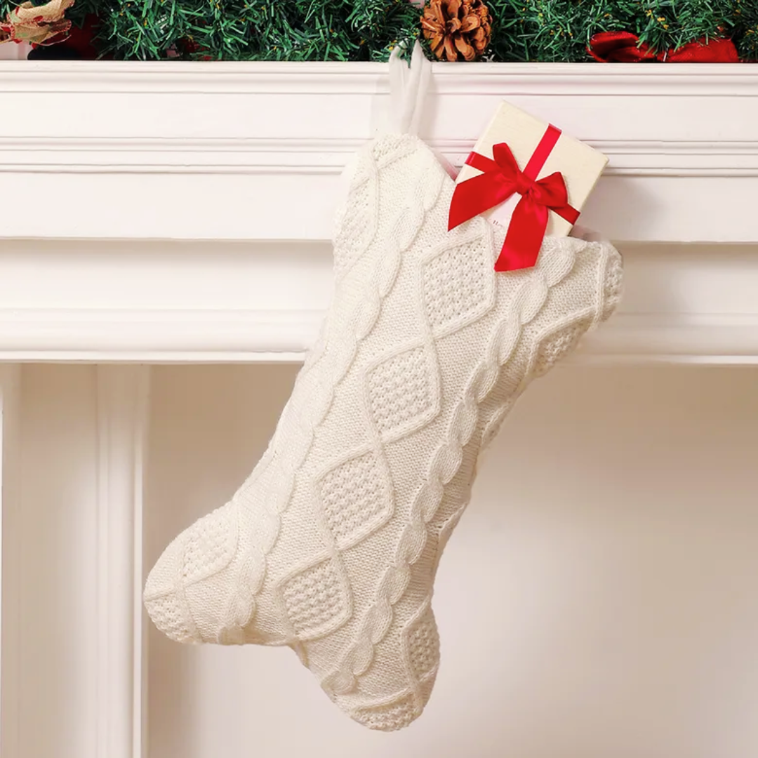 Dog Christmas Stocking. White knitted Christmas stocking with a red bow hanging on a fireplace mantle.