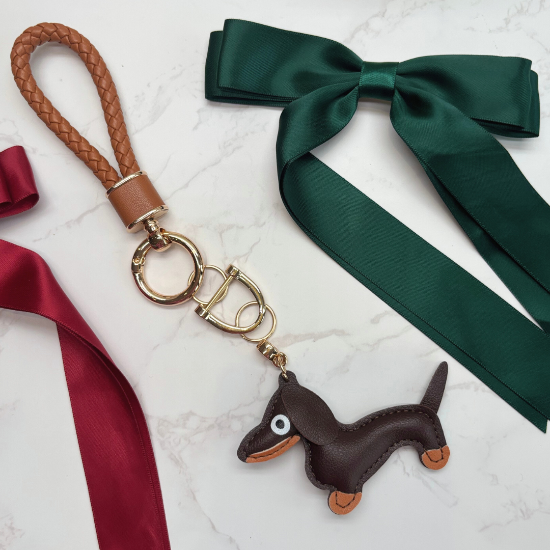 Dog keyring. Keychain with dachshund charm and ribbons on a marble surface