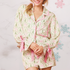 Woman wearing a festive pyjama set with pink accents and ribbon.