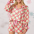 Woman wearing a festive pyjama set with red and pink accents and ribbon.