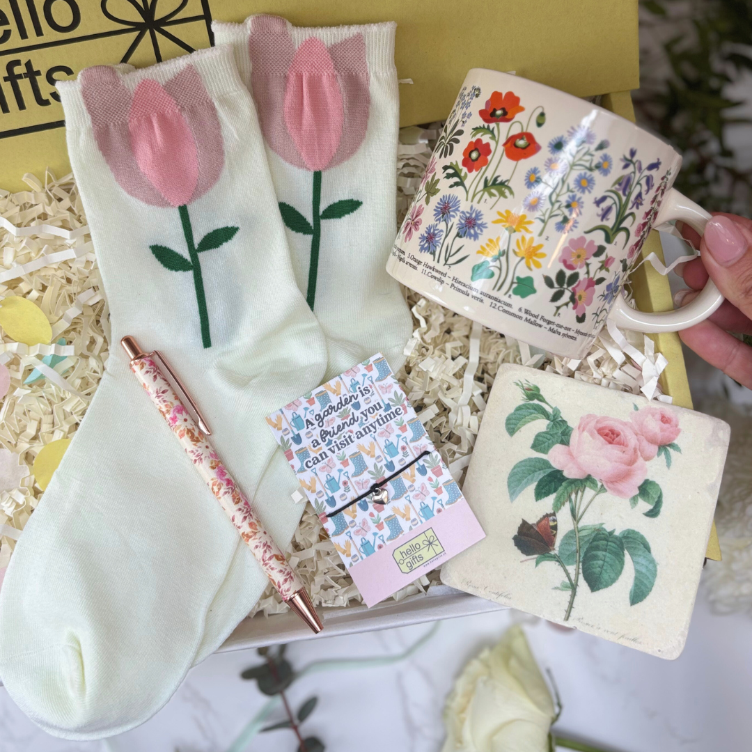 Gift set with floral-themed items including socks, mug, notebook, and pen.
