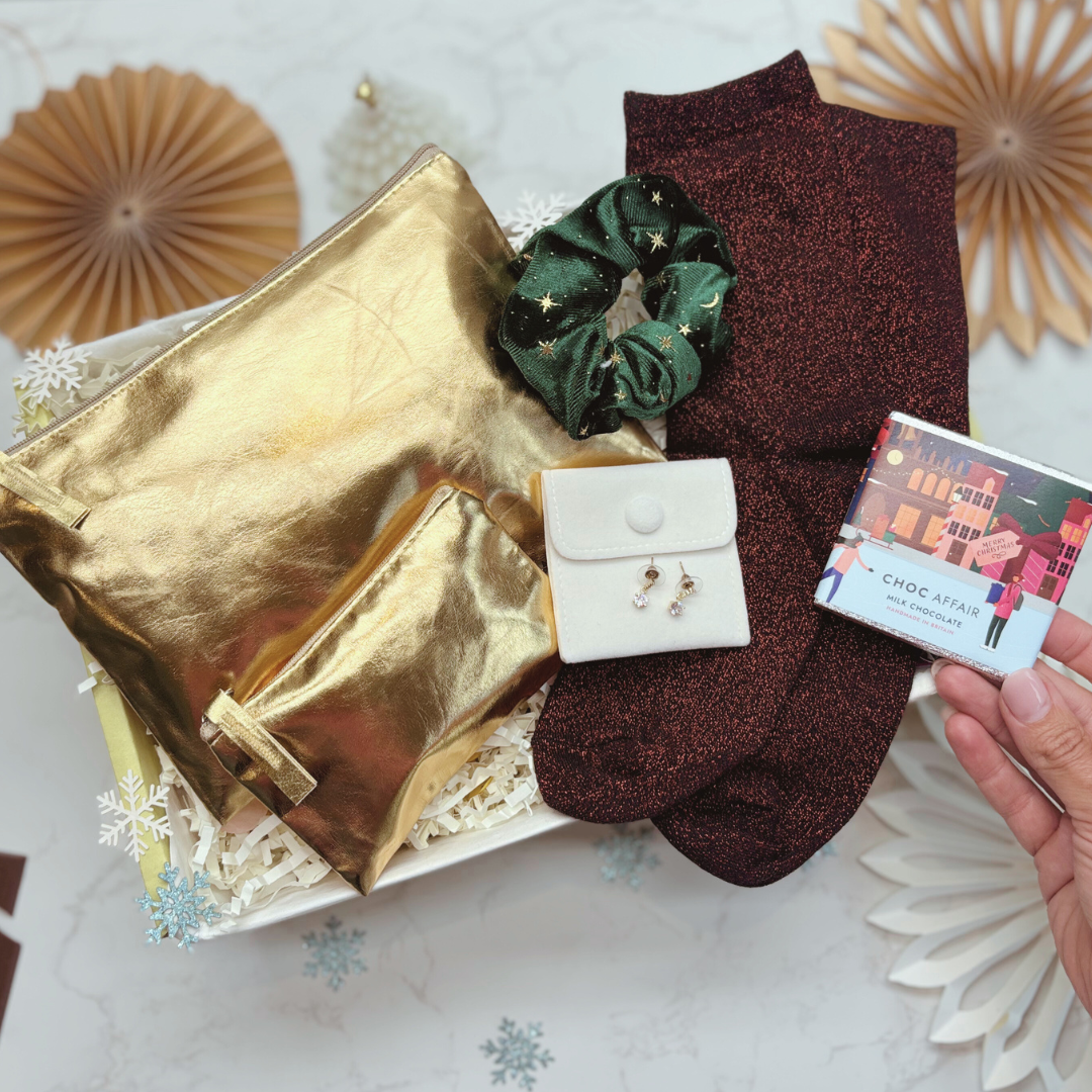 Gold pouch, green scrunchie, brown socks, white jewelry box, and chocolate bar on a decorative surface.