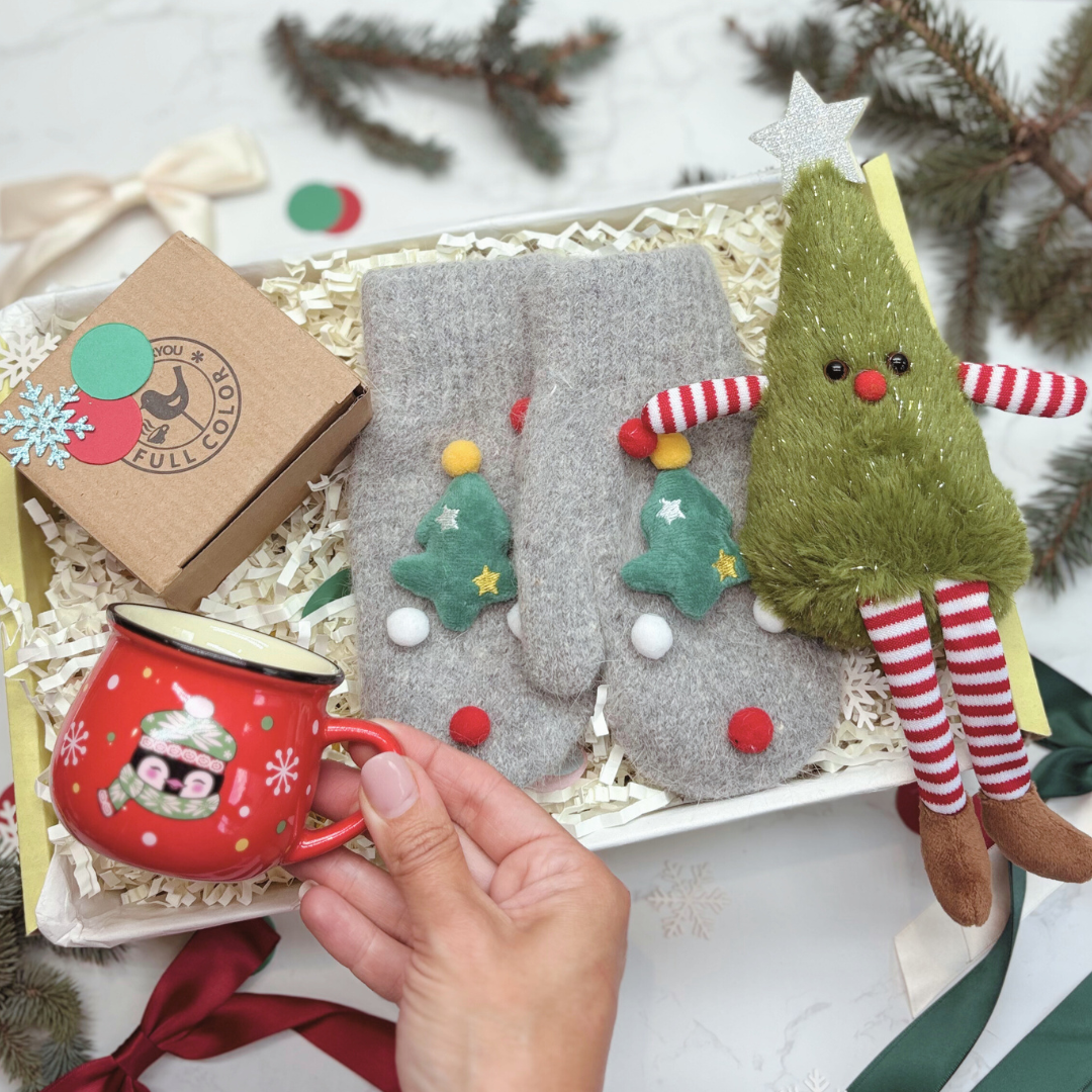 Christmas Eve Box. Christmas-themed gift set with mittens, mug, and decorative tree figure on a white background.
