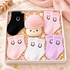 A gift box filled with six pairs of baby socks in black, pink, white, and purple, arranged around a plush pink mushroom toy on a soft beige quilted blanket with confetti.
