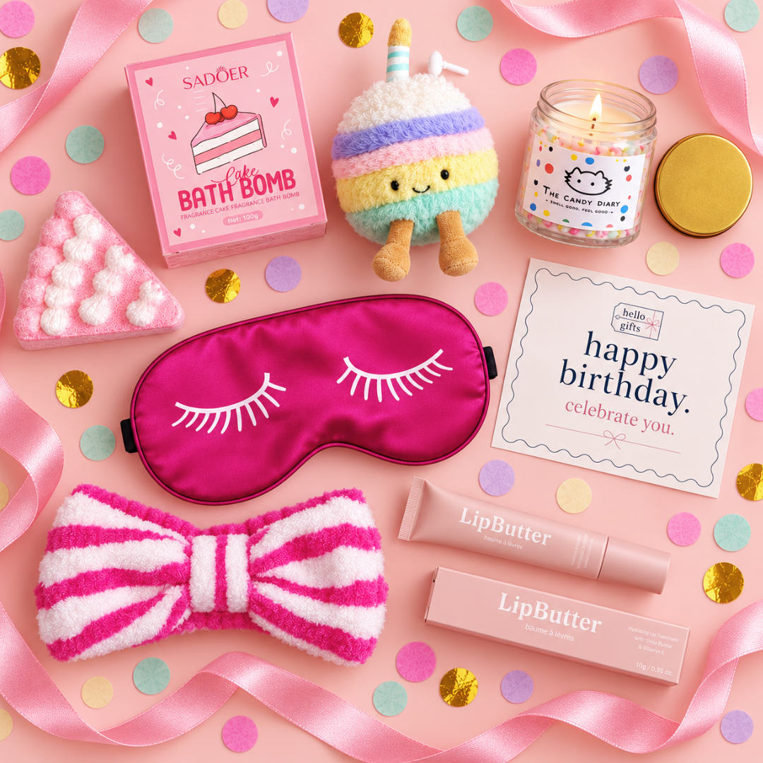 A styled flat-lay of pastel pink birthday-themed beauty and comfort items on a pink background with confetti and ribbon. Visible products include a pink sleep mask with eyelash detail, a pink-and-white striped fuzzy bow, a pink bath bomb box labeled SADOER, a striped plush unicorn toy, a candle jar, a LipButter tube, a LipButter box, and a birthday card.