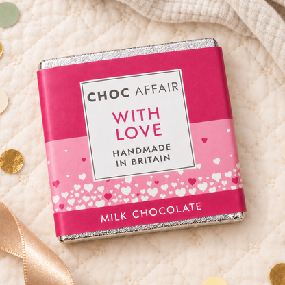 A wrapped milk chocolate bar from Choc Affair, featuring a bright pink and light pink wrapper with white hearts and the text &