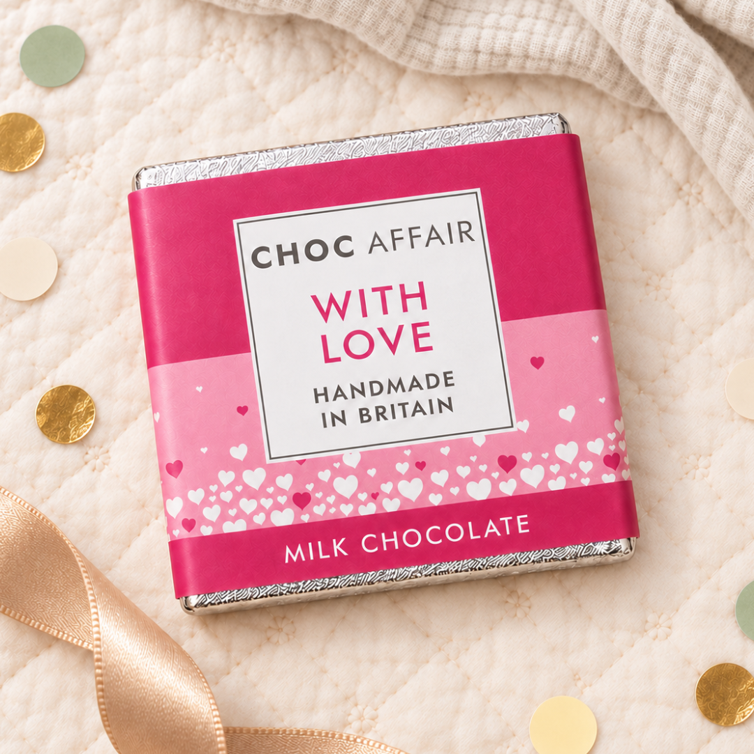 A square milk chocolate bar wrapped in pink and magenta paper packaging with silver foil edges. The front label reads &
