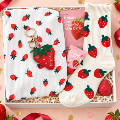 A strawberry-themed gift set in a white box, featuring a white corduroy pouch and a matching white ribbed sock with red strawberries, a red strawberry keychain, a pink skincare book, and a strawberry-themed card, arranged on a pink background with strawberries and confetti.