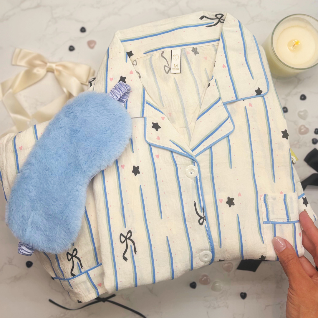 Folded pajama set with fluffy, blue eye mask on a light surface
