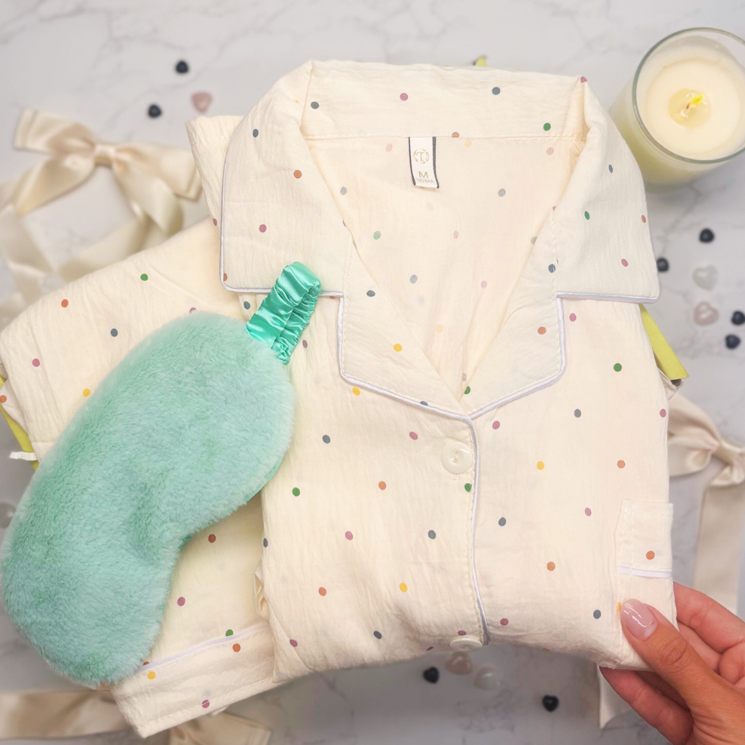 Set of polka dot pajamas and a green eye mask on a gift box background
