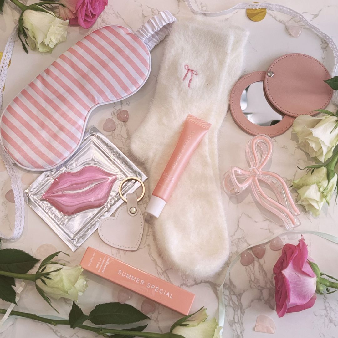 Beauty products including a pink and white striped eye mask, lip balm, and beauty gift box on a floral background.