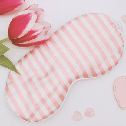 Pink and white striped eye mask with a tulip flower on a light background
