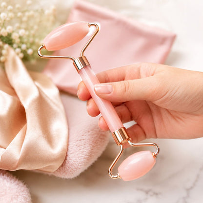 Hand holding a pink and gold facial roller with a soft focus background