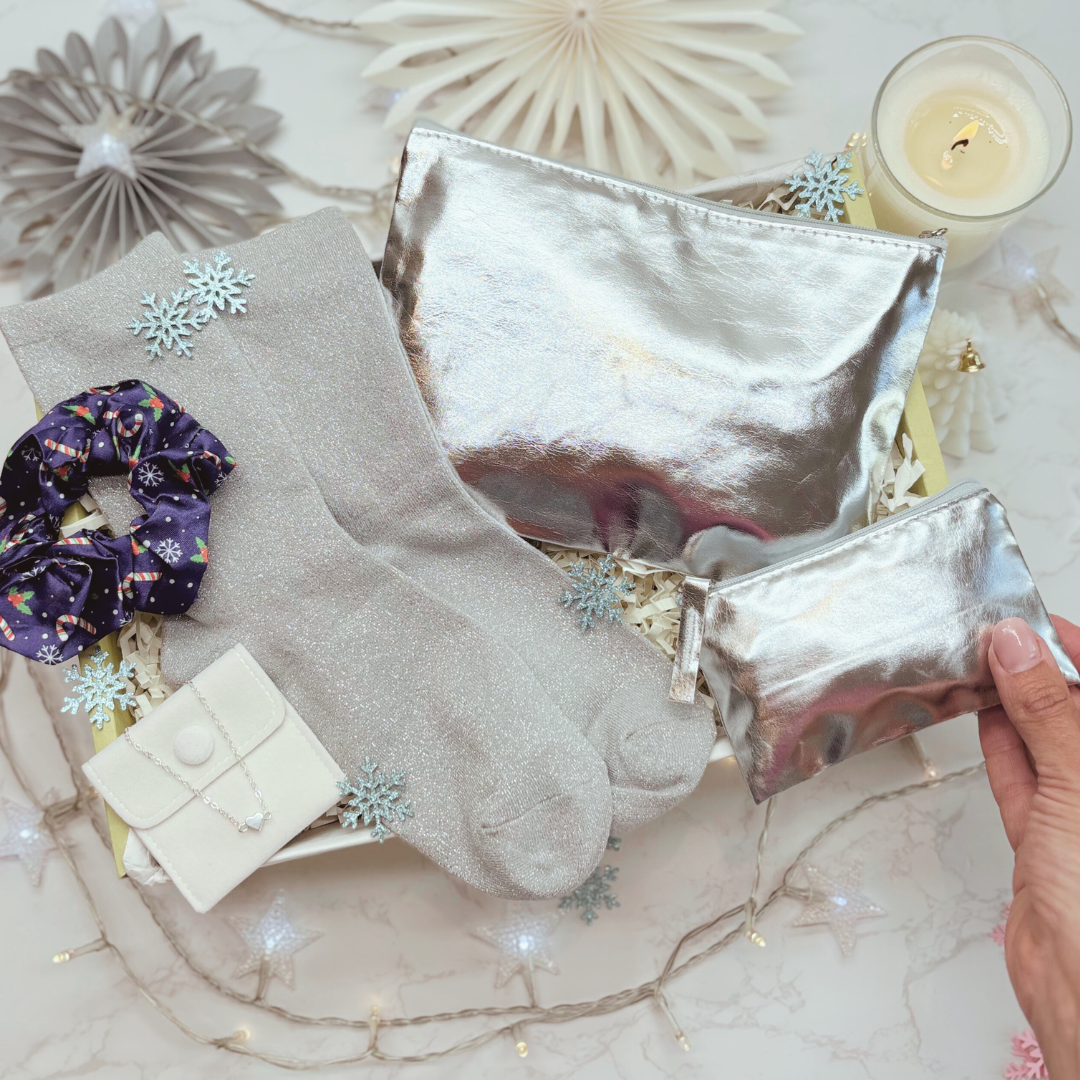 Silver pouches, socks, and a scrunchie on a decorative surface with a candle and snowflake decorations.