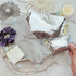 Silver pouches, socks, and a scrunchie on a decorative surface with a candle and snowflake decorations.
