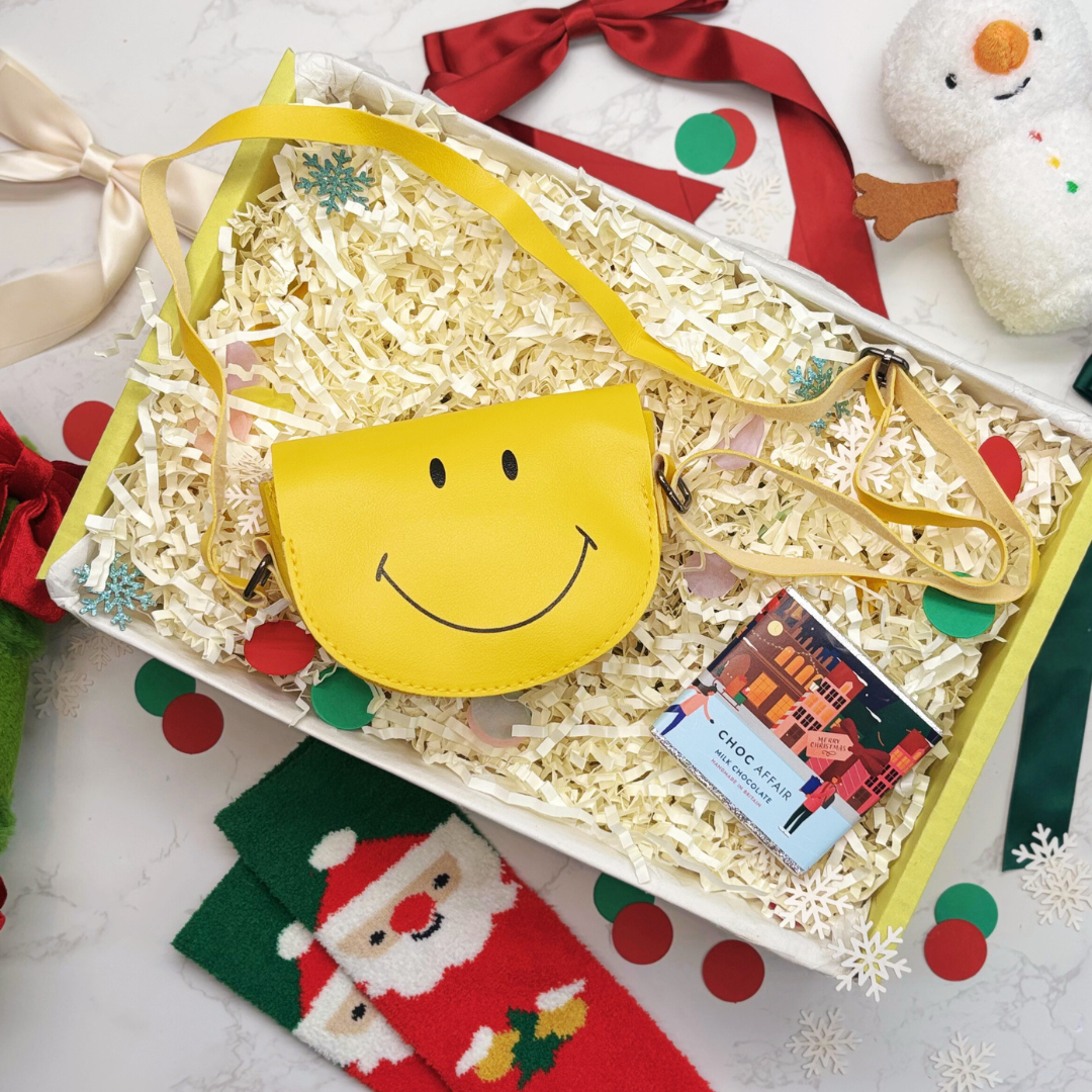 Yellow smiley face bag in a gift box with Christmas-themed items around