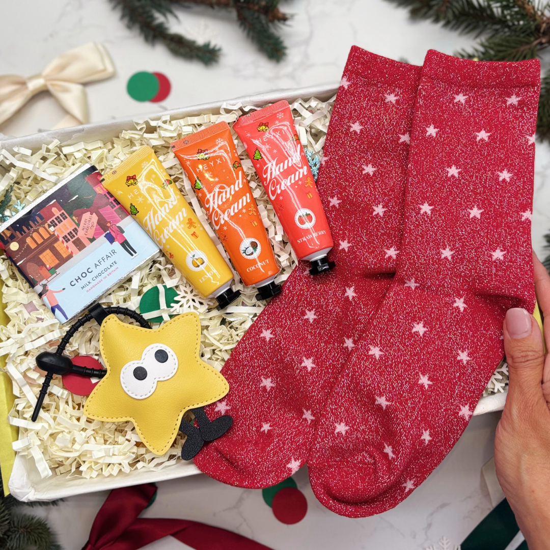 Gift box with red socks, lip balms, and a star-shaped keyring in a yellow gift box.