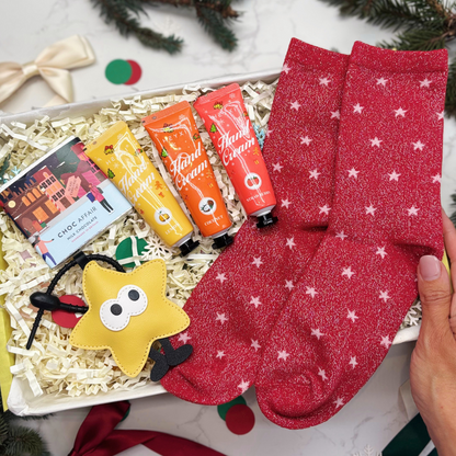 Gift box with red socks, lip balms, and a star-shaped keyring in a yellow gift box.
