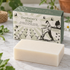 A rectangular bar of off-white soap placed in front of its illustrated green and cream packaging box labeled &