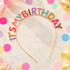 A gold metal headband decorated with colorful, raised letters spelling &