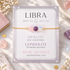 A gold chain bracelet with three beads (pink opalite, purple lepidolite, and light blue rose quartz) displayed on its lavender card, which lists astrological meanings for Libra.