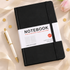 A black hardcover notebook with a white paper band label reading &