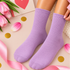 A pair of light purple ribbed crew socks worn on feet, styled with pink tulips, gold confetti, pink ribbon, and a pink card in a flat-lay composition.