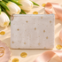 A light gray velvet zipper pouch decorated with gold star and dot patterns, styled on a beige surface with white tulips, gold confetti, a pink satin ribbon, and a pink ring dish.