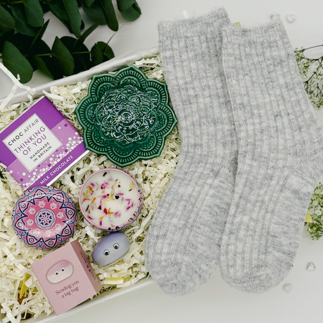 A gift set containing grey thick socks, a green ceramic mandala trinket tray, a purple &