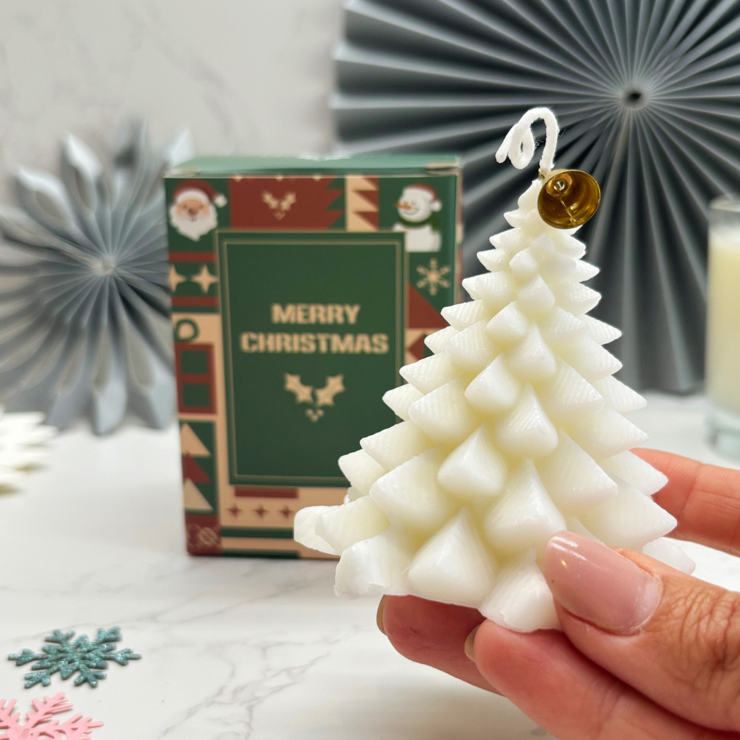 White Christmas tree-shaped candle held by a hand with a &